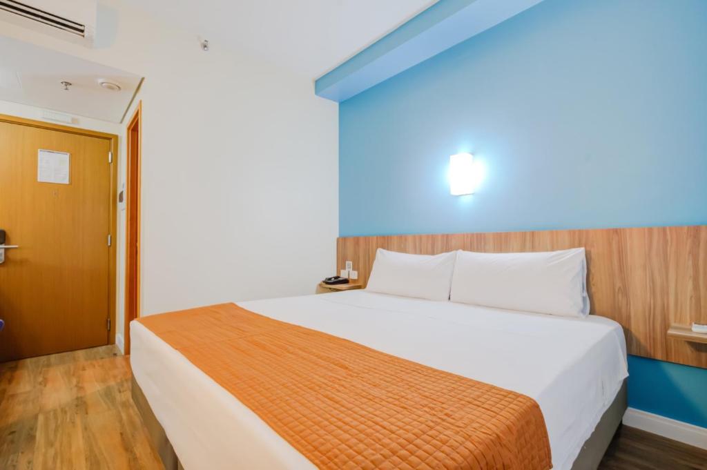 a bedroom with a large white bed with a wooden headboard at Go Inn Cambuí Campinas in Campinas