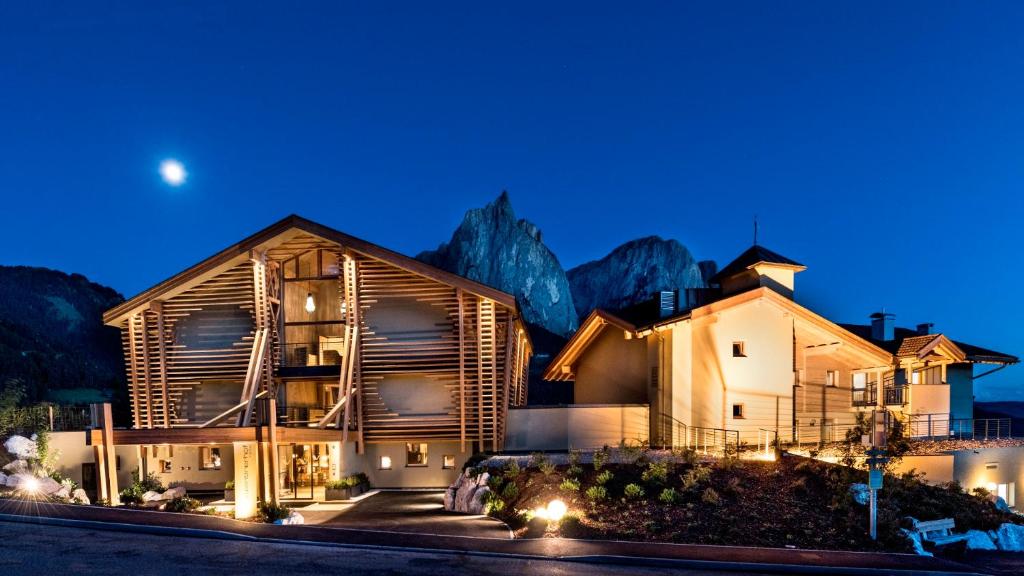 ein Haus mit Bergen im Hintergrund nachts in der Unterkunft Hotel Valentinerhof in Seis am Schlern