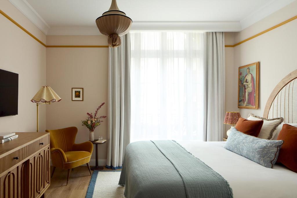 sypialnia z łóżkiem, krzesłem i oknem w obiekcie Le Grand Hôtel Cayré w Paryżu