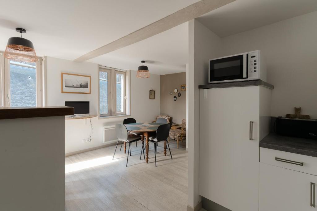 a kitchen and dining room with a table and a microwave at Studio et appartements Sainte Catherine in Honfleur