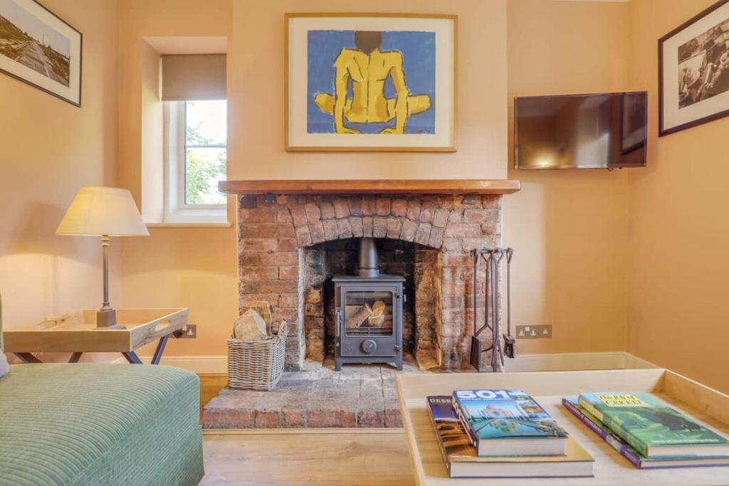 a living room with a fireplace and a tv at Gardeners Cottage - Hot Tub Packages Available in Market Harborough