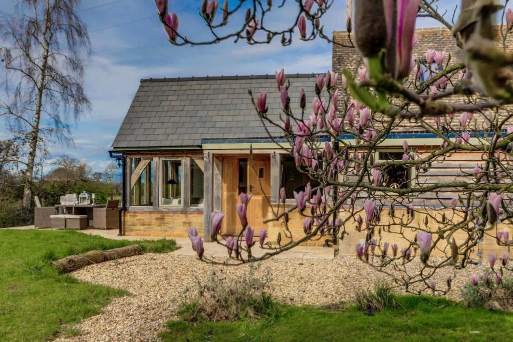 a house with a flowering tree in front of it at Honeysuckle Cottage - Hot Tub Packages Available in Weston Subedge