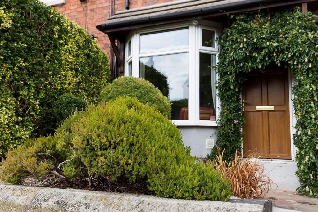 a house with a brown door and some bushes at Hygge House Cosy 3 Bedroom 2 Bathroom Townhouse in Kegworth