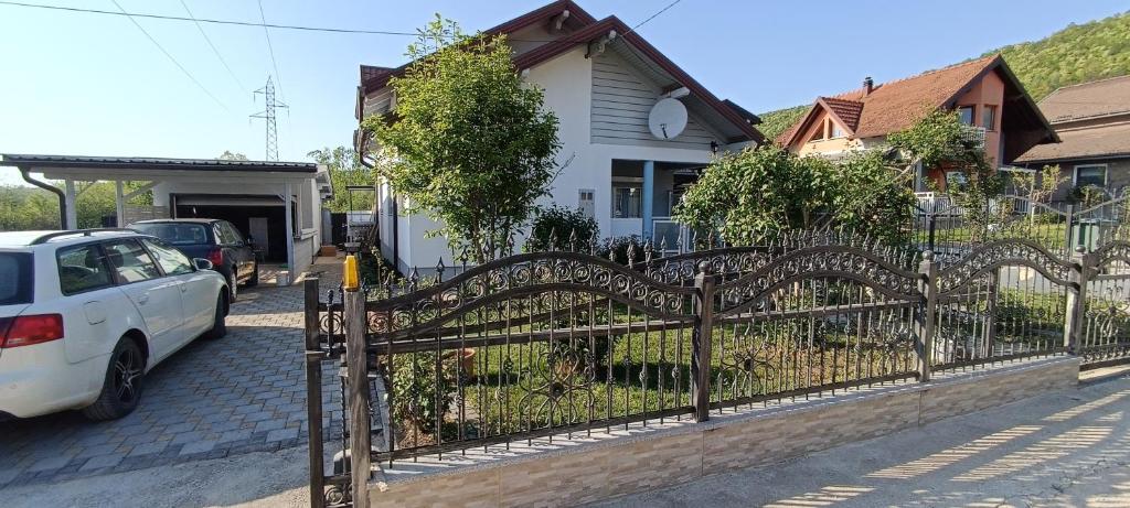 a fence in front of a white car parked in front of a house at Apartment Deluxe Holiday in Bihać