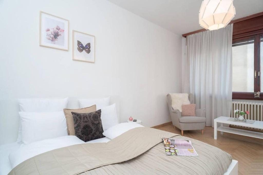 ein weißes Schlafzimmer mit einem großen Bett und einem Stuhl in der Unterkunft Convenient apartment in the heart of downtown in Budapest