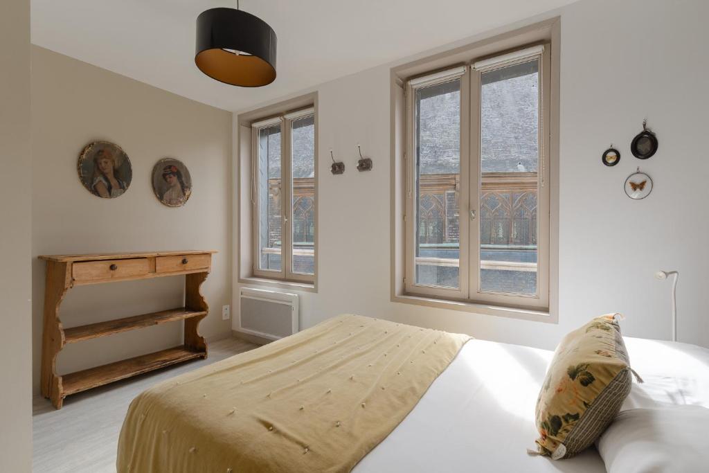a bedroom with a bed and two windows at Studio et appartements Sainte Catherine in Honfleur