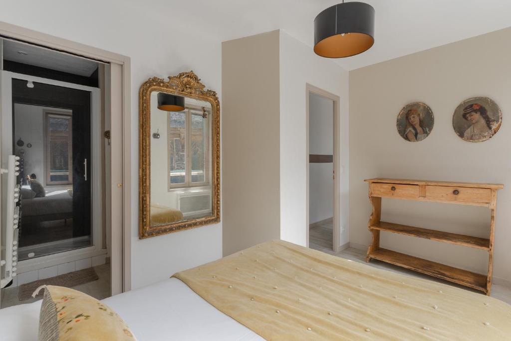 - une chambre avec un lit et un miroir mural dans l'établissement Studio et appartements Sainte Catherine, à Honfleur