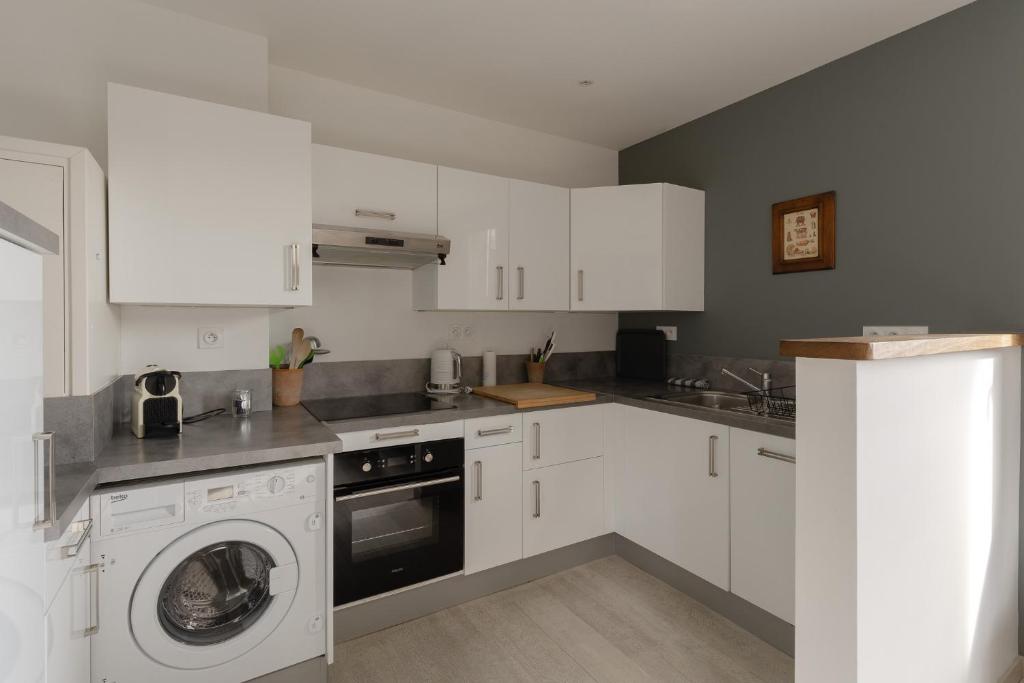 a kitchen with white cabinets and a washing machine at Studio et appartements Sainte Catherine in Honfleur