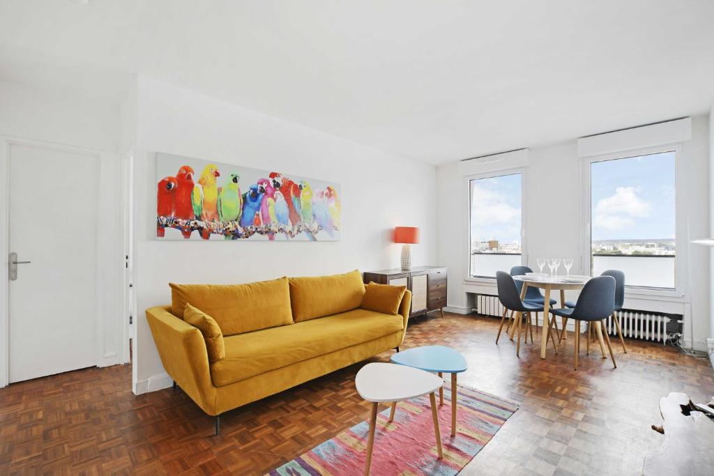 a living room with a yellow couch and a table at Amazing panoramic view facing Parc de La Villette - Apartment 4P in Paris