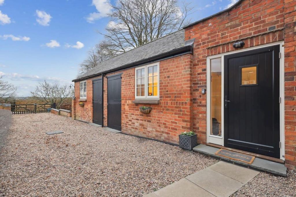 a brick house with a black door on it at Squirrel Lodge - 2 Bed Country Home in Market Harborough