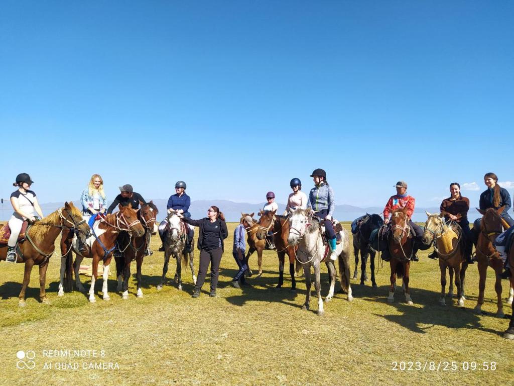 een groep mensen op paarden in een veld bij Zalkar Yurt Camp in Song-Kul