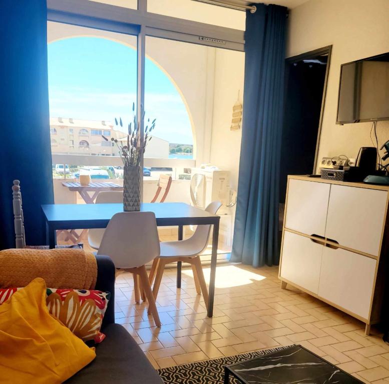 a living room with a table and a kitchen at Appartement climatisé à deux pas de la plage in Port Leucate