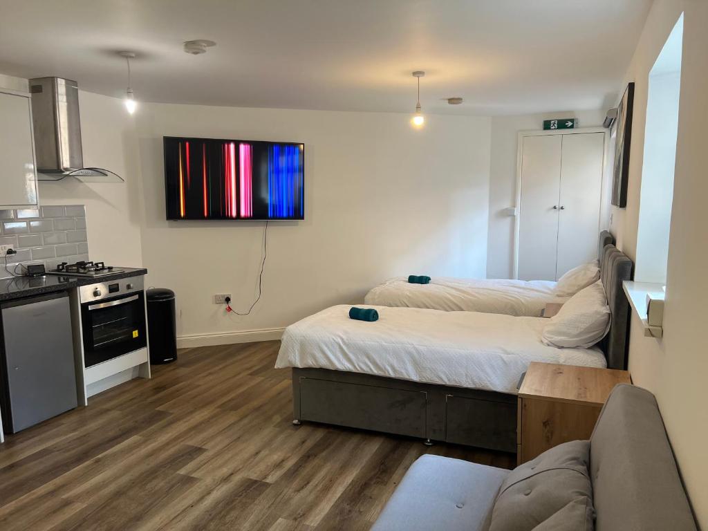 uma sala de estar com 2 camas e uma cozinha em Elegant Central Luton Studio - Contractors/Airport Travellers! em Luton