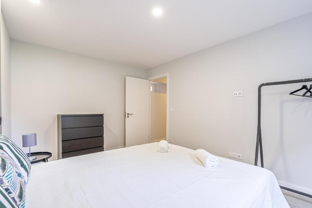 a white bedroom with a bed and a mirror at JMF House in São Vicente