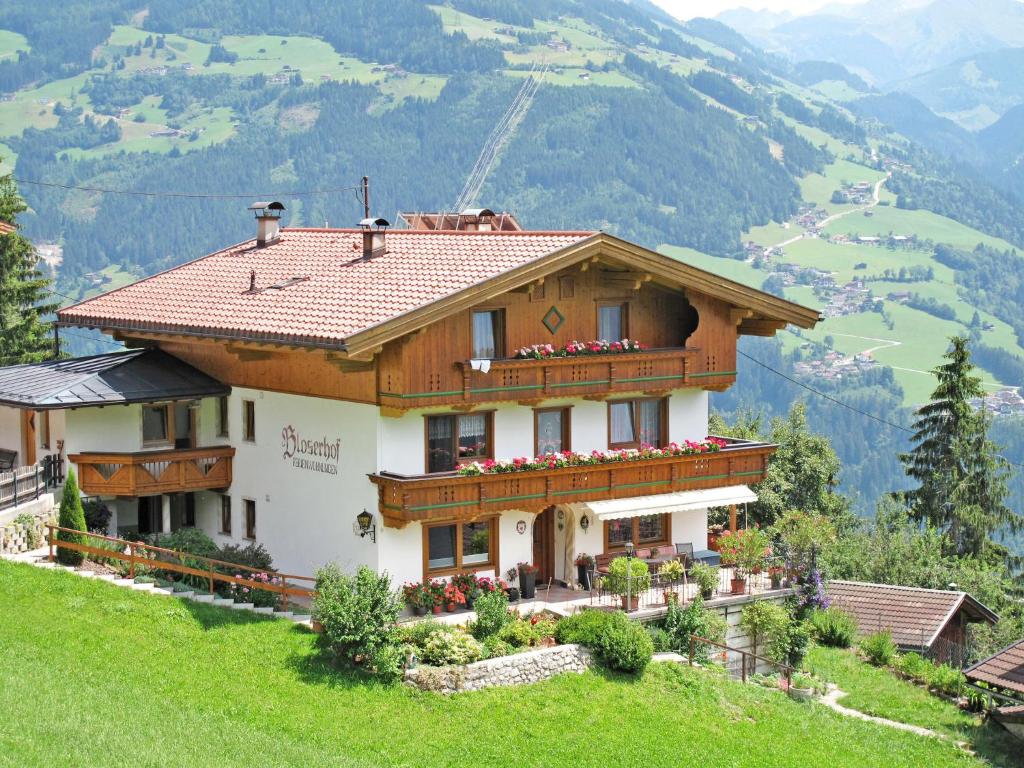 a house on a hill with mountains in the background at Apartment Bloserhof - ZAZ412 by Interhome in Zellberg