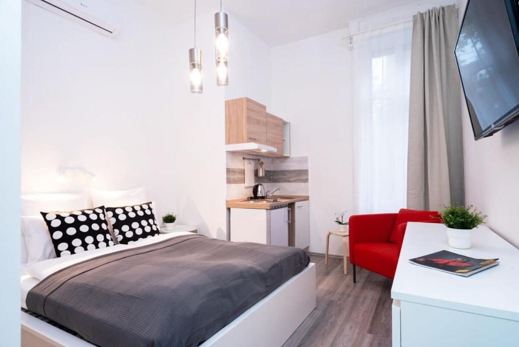 een slaapkamer met een bed en een rode stoel bij New comfy studio at convenient location in Boedapest