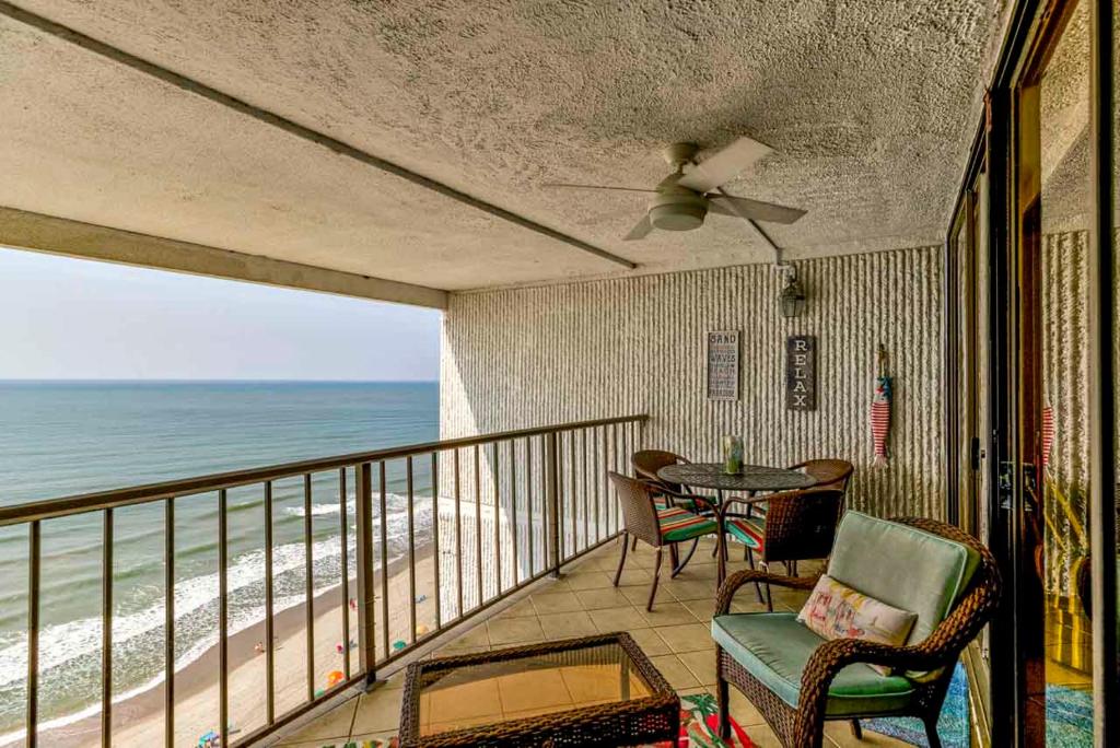 a balcony with a table and chairs and the beach at Oceanfront Custom and what a view of the ocean in Myrtle Beach