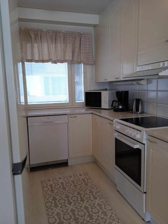 a kitchen with white cabinets and a stove and a window at Einonhovi in Ylivieska