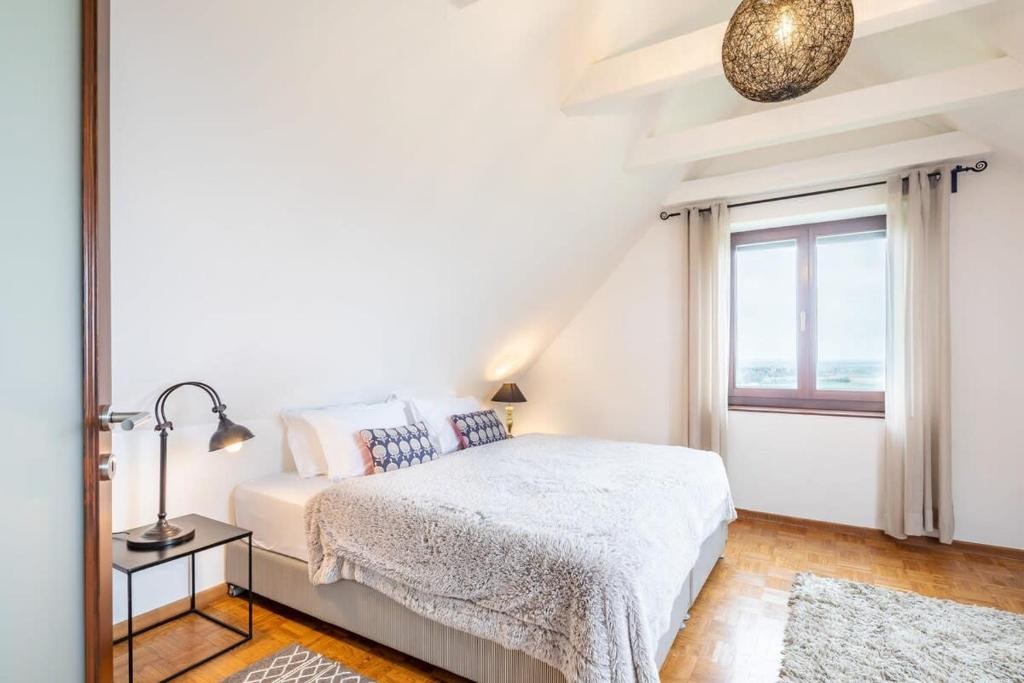 a white bedroom with a bed and a window at Slow living - perfect vacation in Somlószőlős