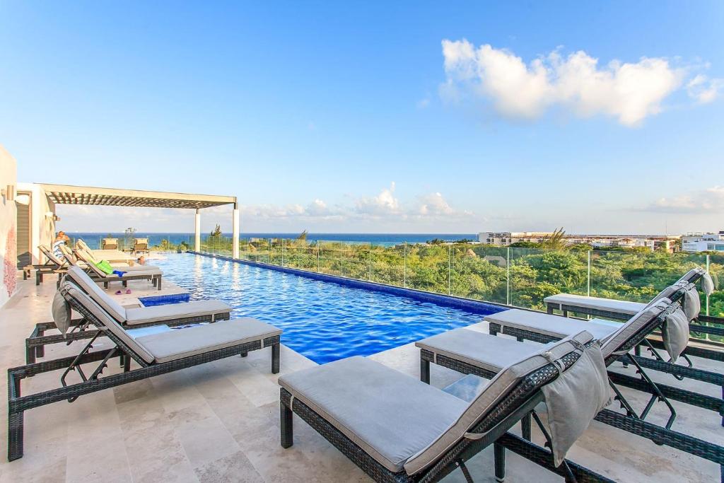 a swimming pool with chairs and a view of the ocean at Happy Vibes Getaway with Stellar Oceanview Roof Pool! in Playa del Carmen