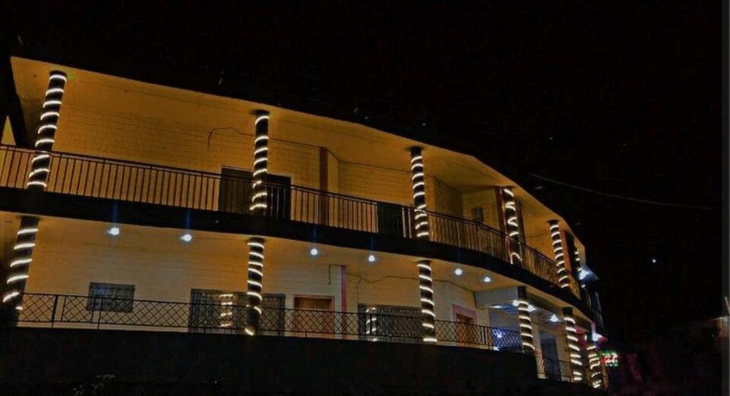 a building with lights on its balcony at night at Al Sadiq Guest House in Murree