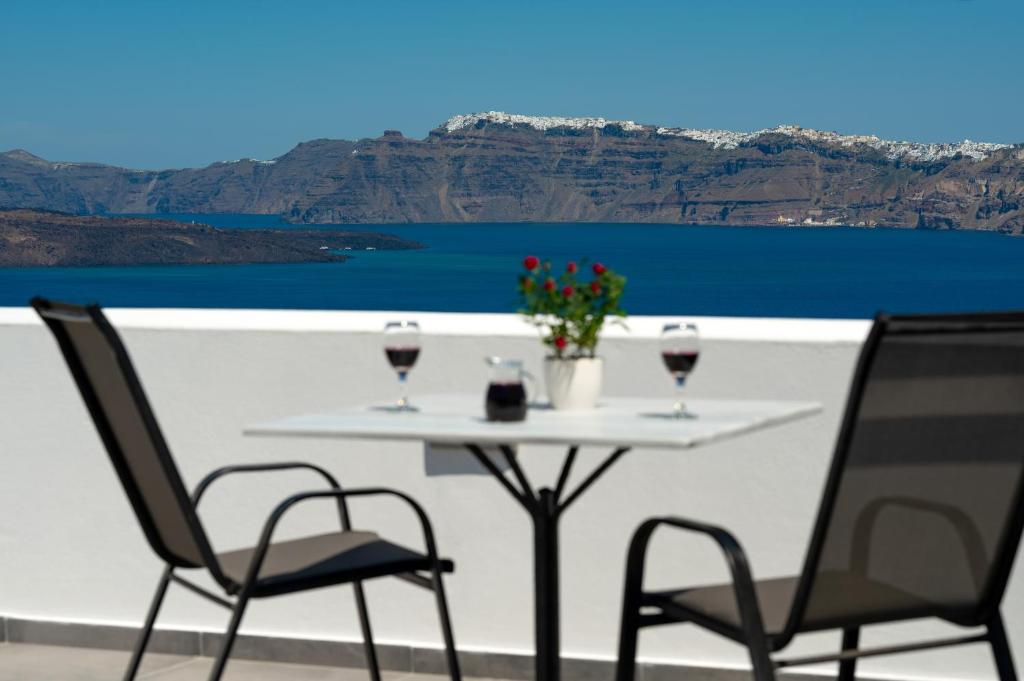 a table with two glasses of wine on a balcony at Pancratium Villas & Suites in Akrotiri