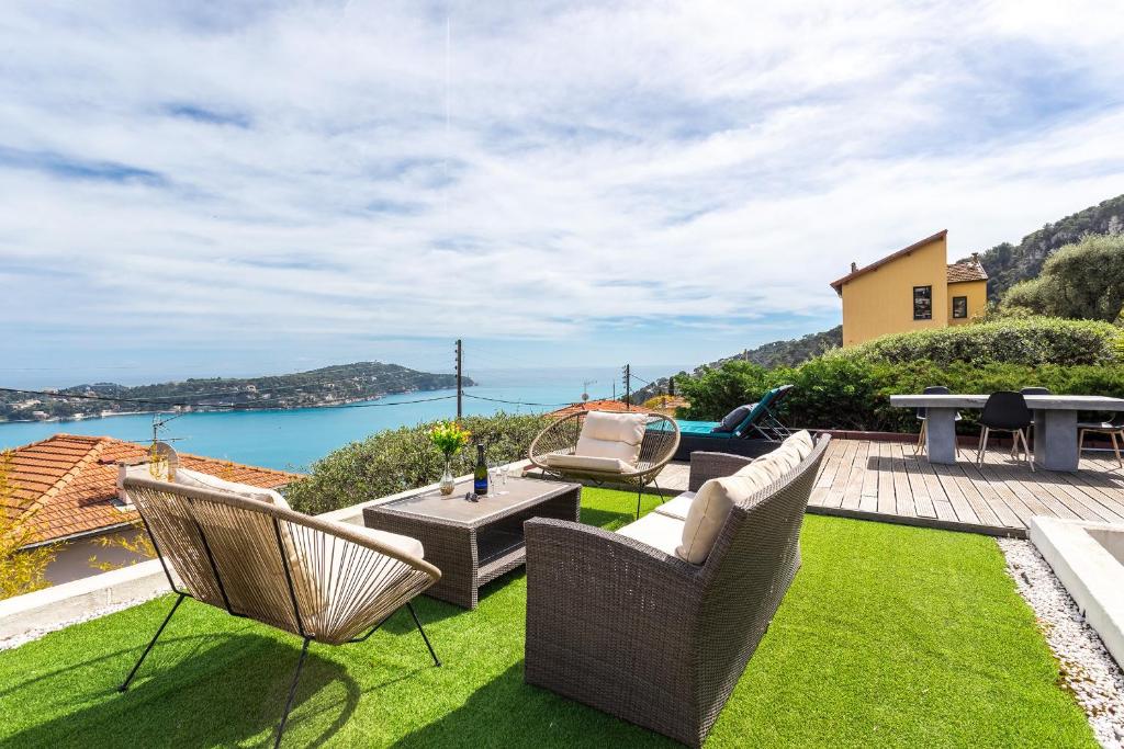 a patio with chairs and a table and a view of the water at VILLA MARGUERITE VI4406 By Riviera Holiday Homes in Villefranche-sur-Mer