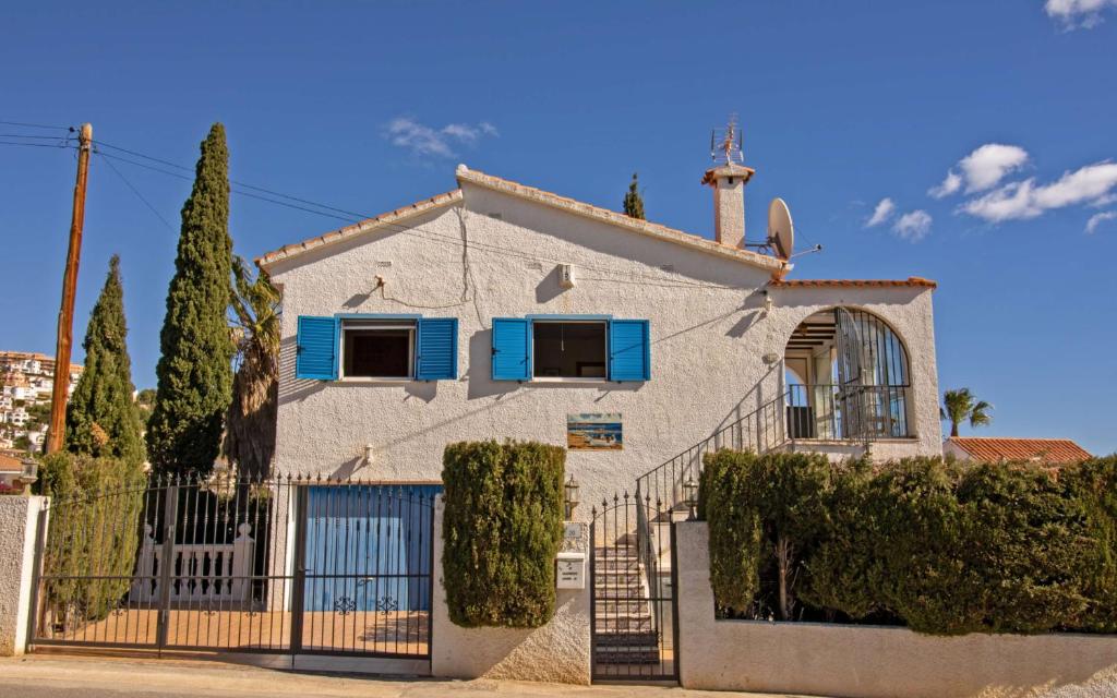 a white house with blue windows and a fence at Villa privada a 350 metros del mar ALCOSSEBRE Albert Villas in Alcossebre