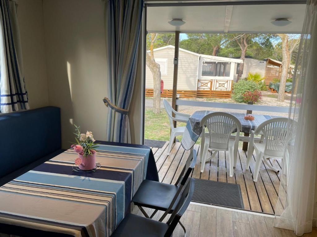 a living room with a table and chairs and a patio at Mobilhome au coeur de la Camargue in Le Grau-du-Roi