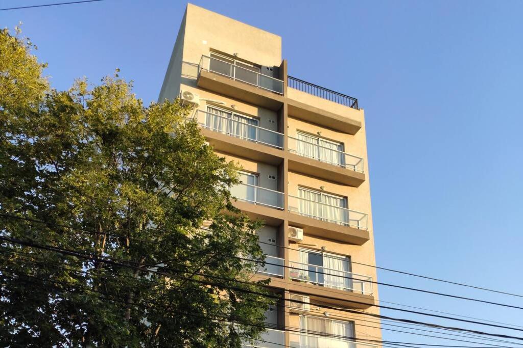 un edificio de apartamentos alto con balcones y un árbol en Fortunati Departamentos en San Miguel