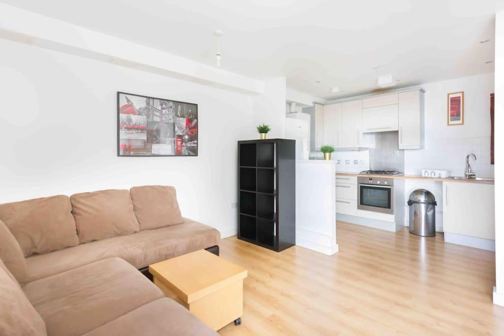 a living room with a couch and a kitchen at Spacious 2 Bedroom Apartment In Central Near tube in London