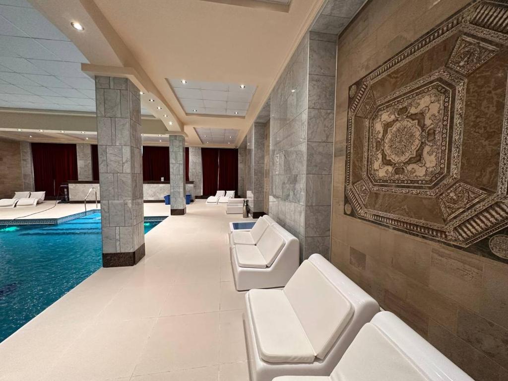 a lobby with a pool with white chairs and a wall at Status Hotel in Río Grande