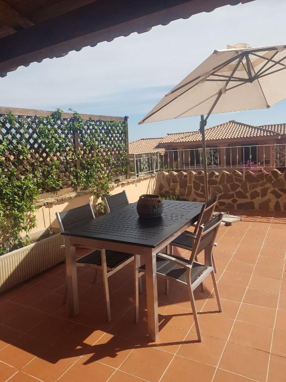 a table and chairs with an umbrella on a patio at Sardegna Casa Ruby Baia de bahas Marinella in Santa Marinella