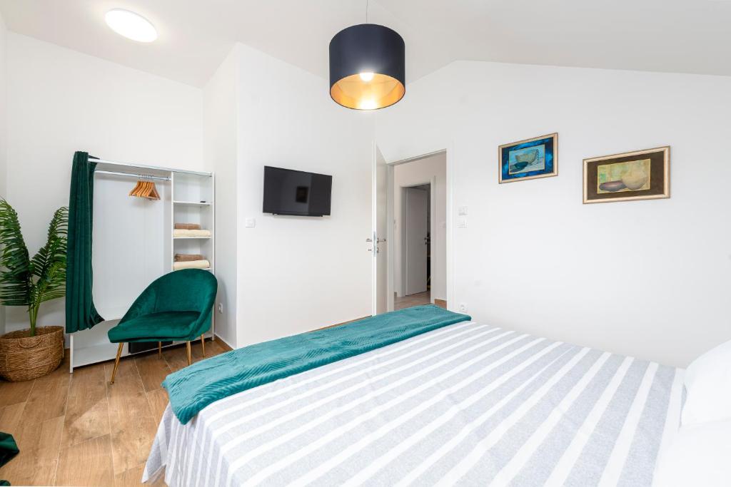 a bedroom with a bed and a green chair at Apartman Lara in Obuljeno