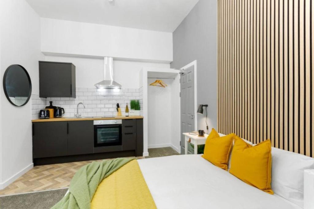 a bedroom with a bed with yellow pillows and a kitchen at Nottingham Group Stay - 8 x Studio Apartments, sleeps 16, Free Parking in Nottingham