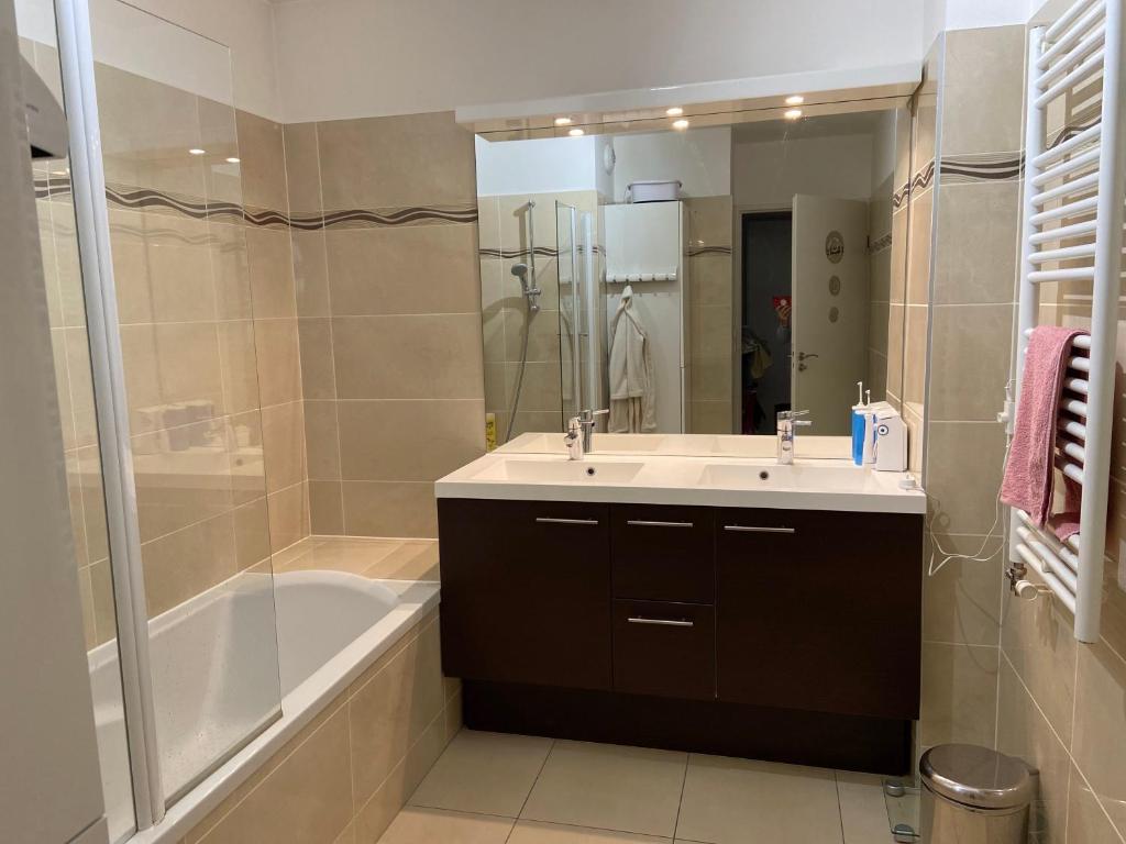 ein Badezimmer mit einer Badewanne, einem Waschbecken und einer Badewanne in der Unterkunft Chaleureux et lumineux appartement in Puteaux