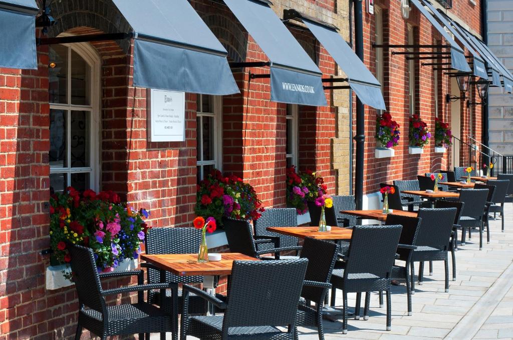 a row of tables with umbrellas in front of a brick building at Ennios Boutique Hotel in Southampton