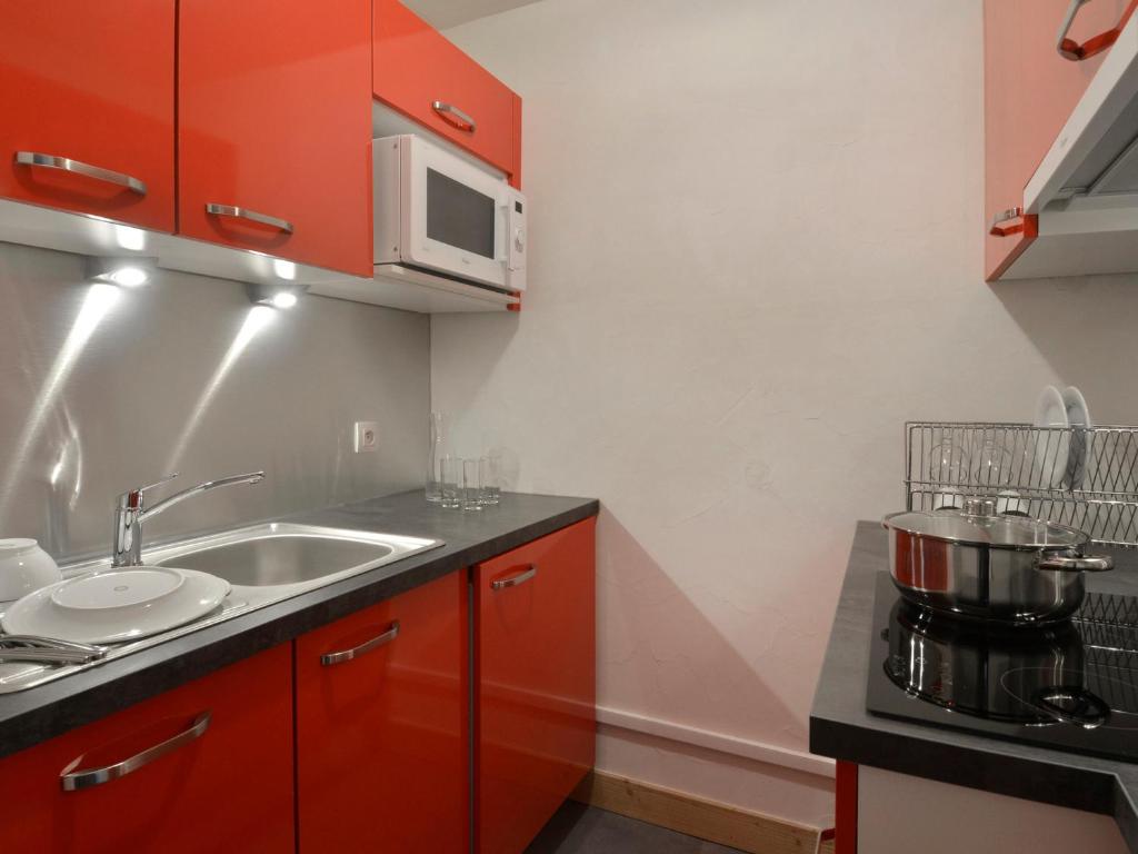 cocina con armarios rojos, fregadero y microondas en Appartement Plagne Bellecôte, 2 pièces, 5 personnes - FR-1-181-2014 en La Plagne Tarentaise
