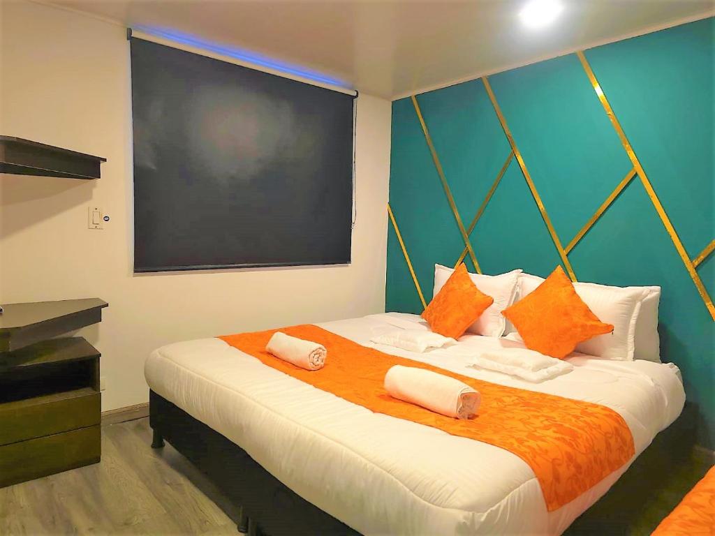 a bedroom with a large bed with orange and white pillows at Hotel Kristal Ferial in Bogotá