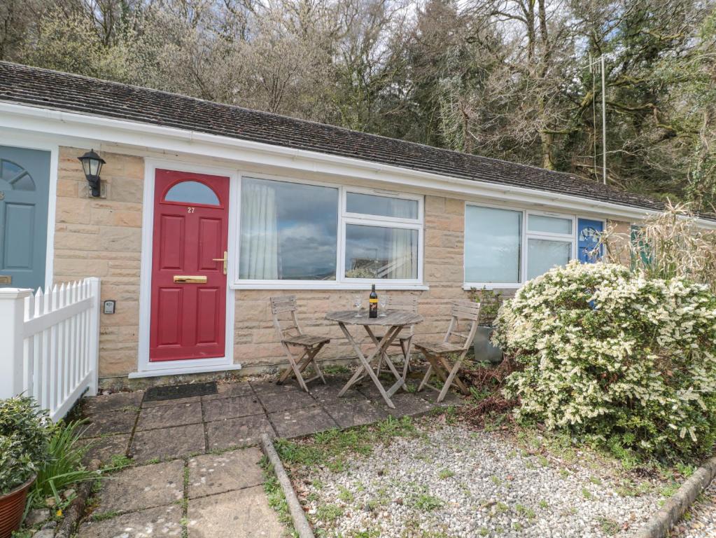 ein kleines Haus mit einer roten Tür und einem Tisch in der Unterkunft 27 Fernhill Heights in Bridport
