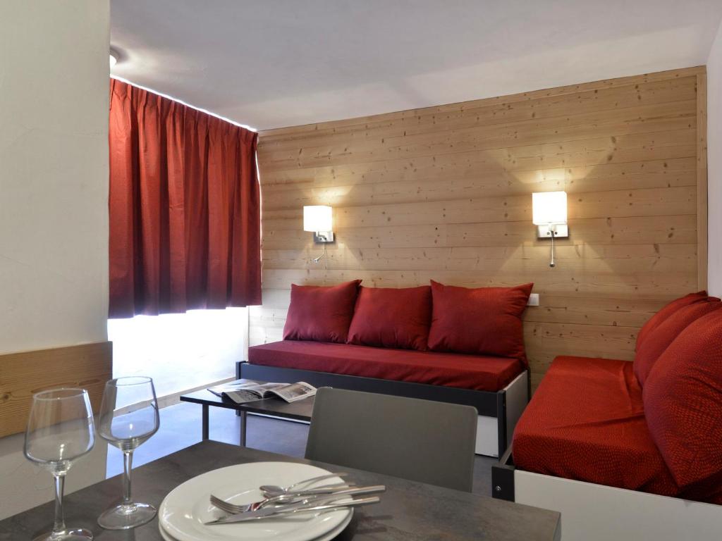 a living room with a red couch and a table at Appartement Plagne Bellecôte, 2 pièces, 5 personnes - FR-1-181-2426 in La Plagne Tarentaise