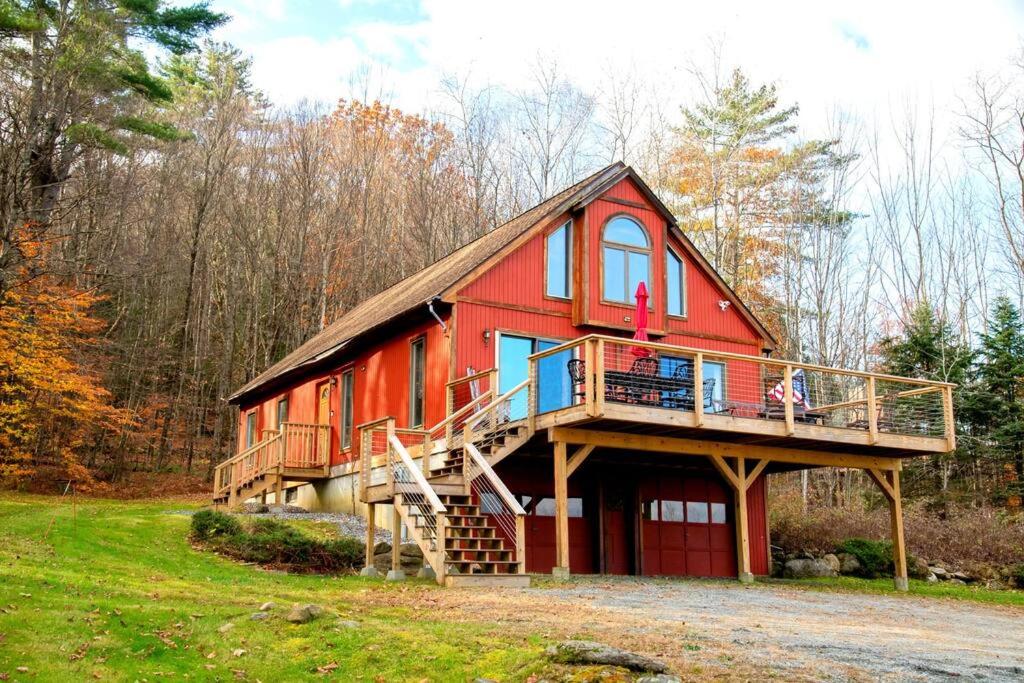ein rotes Haus mit einem Gamer-Dach und einer Terrasse in der Unterkunft WhiSki Cabin *12-acres with mountain views!* in Chester
