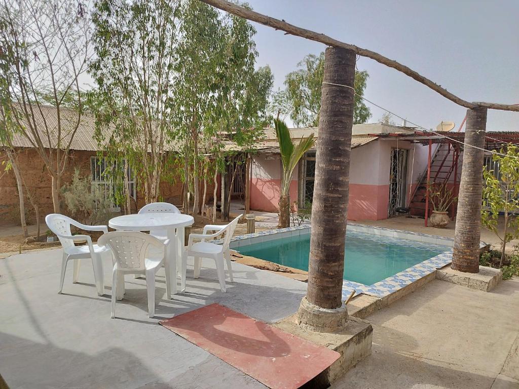 un patio con mesa y sillas junto a una piscina en La Maison Blanche en Ndangane