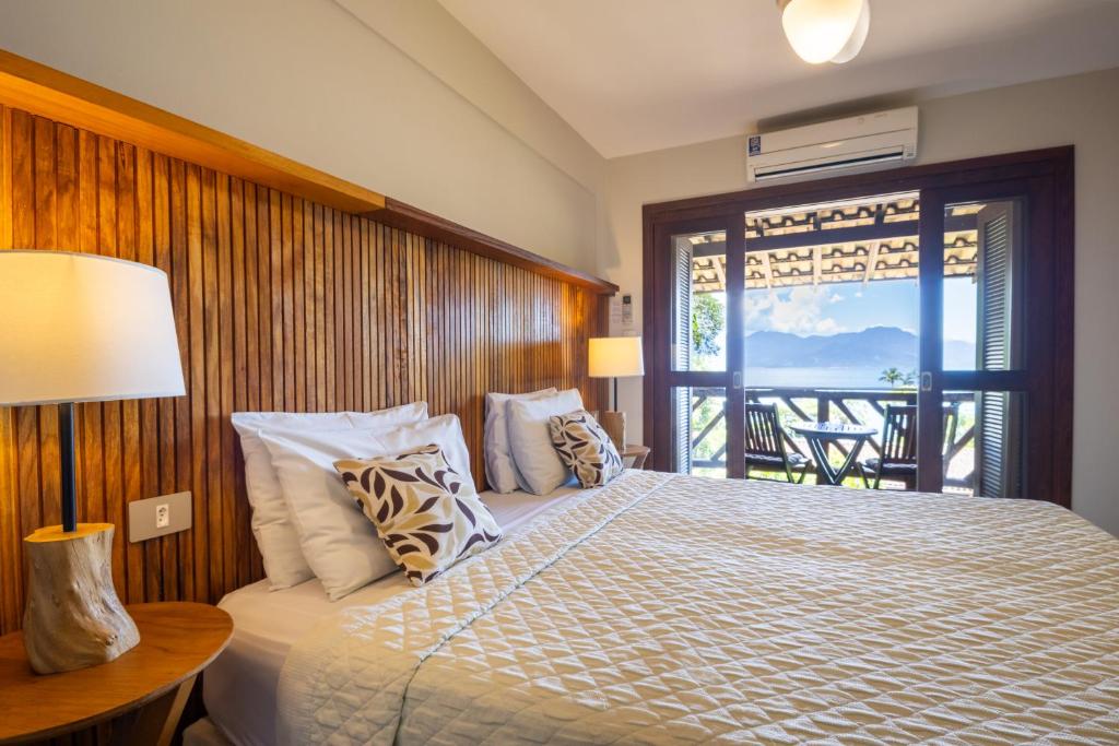 a bedroom with a bed with a view of a balcony at Pousada Naturalia in Abraão
