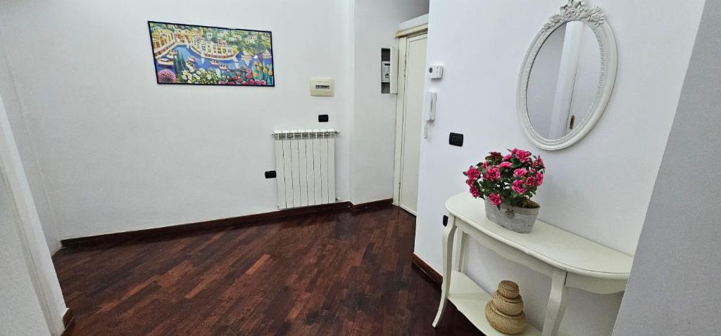 a hallway with a mirror and a table with flowers at APPARTAMENTO CHIATAMONE 26 in Naples
