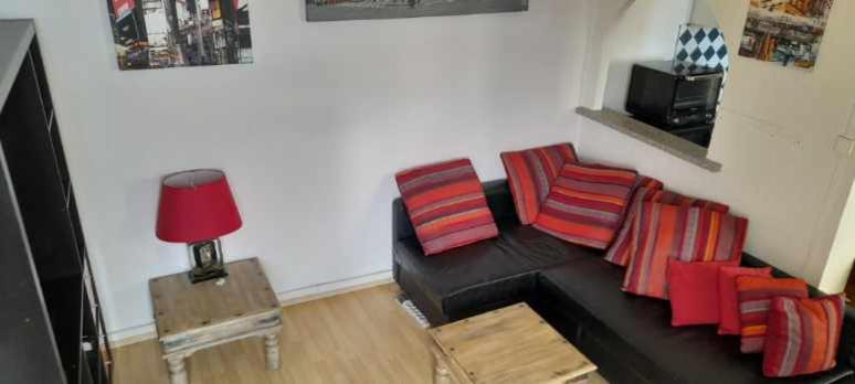sala de estar con sofá negro y almohadas coloridas en Mer&Soleil en Sète