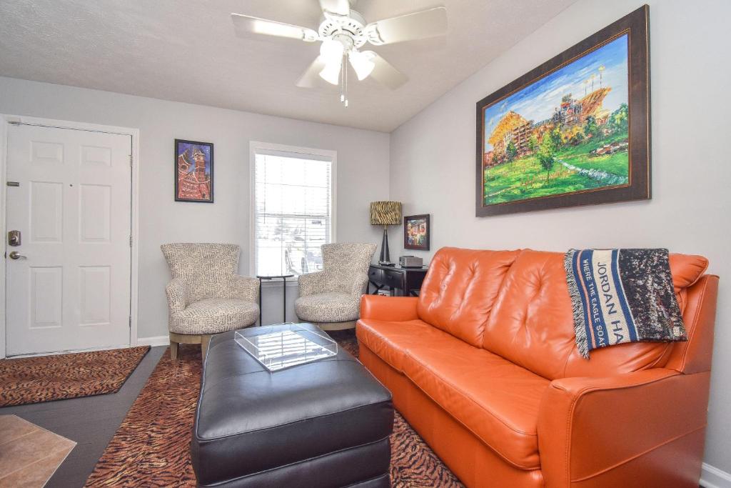 a living room with an orange couch and a chair at Stadium View in Auburn