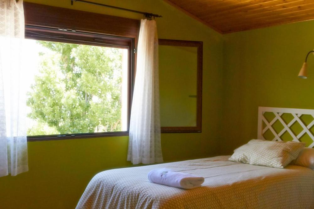 Dormitorio verde con cama y ventana en CASA RURAL EL PINICO en Yeste