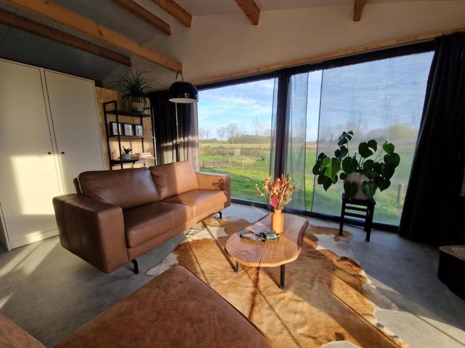 - un salon avec un canapé en cuir et une table dans l'établissement De Wilde Tuin - Tuinkamer, à Moergestel