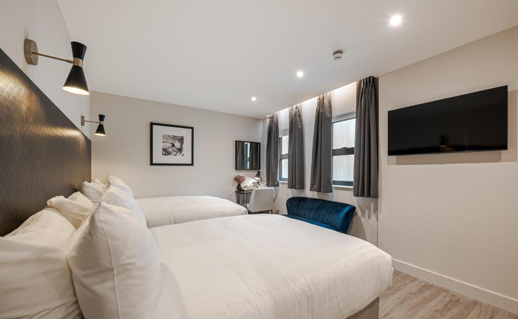 a bedroom with two beds and a flat screen tv at King's Cross Express Inn in London